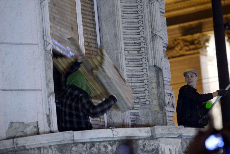Egy tüntető a redőnyt rongálja a Fidesz Lendvay utcai székházának erkélyén, ahol a résztvevők egy csoportja régi számítástechnikai eszközökkel dobálták az épületet 2014. október 26-án. (MTI Fotó: Beliczay László)