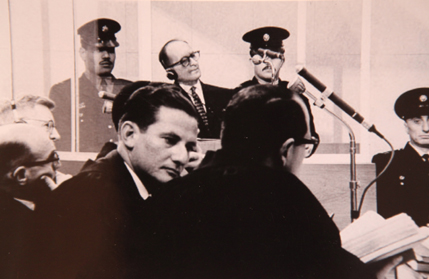 Gabriel Bach (a kamerába néz) és Adolf Eichmann (fejhallgatóval) a bíróságon. Foto: GPO