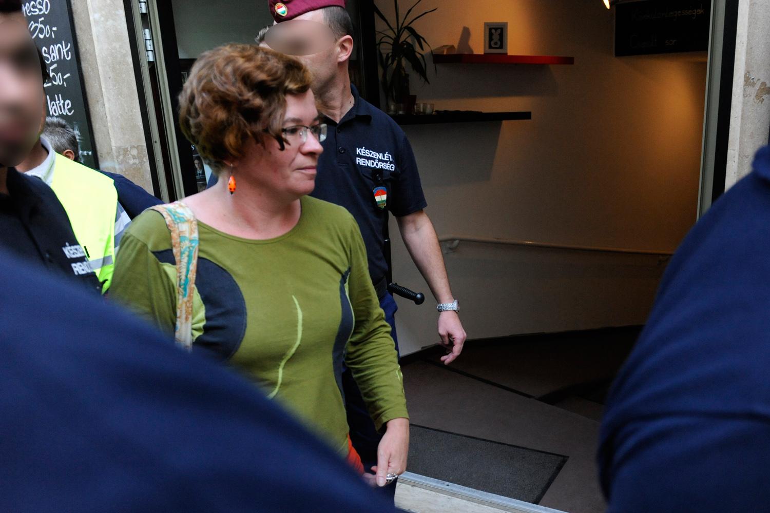 A hírhedt felvétel: rendőrök kísérik el munkahelyéről Móra Verát, az Ökotárs Alapítvány vezetőjét, hogy házkutatást tartsanak otthonában. 